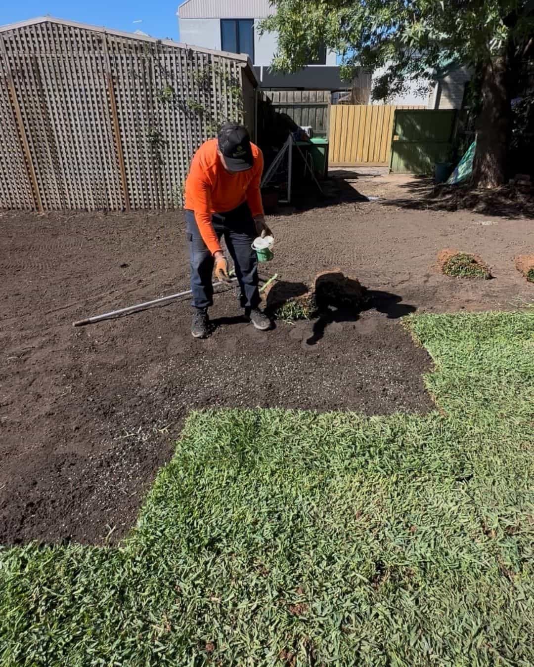 Turf installation underway in a Northcote backyard with prepared soil and sections of new lawn being laid
